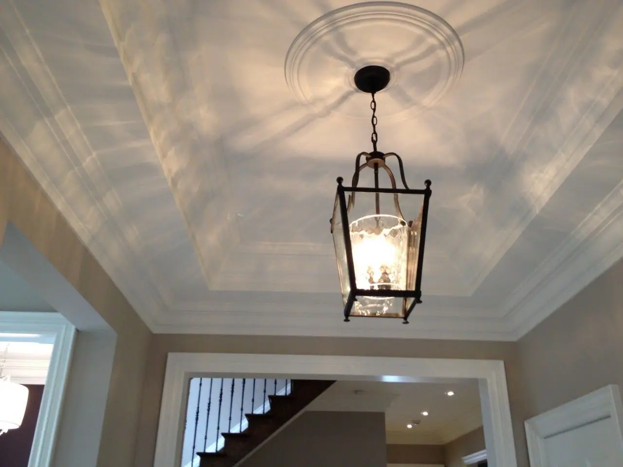 A tray ceiling with a ceiling medallion and a lantern-style pendant light.