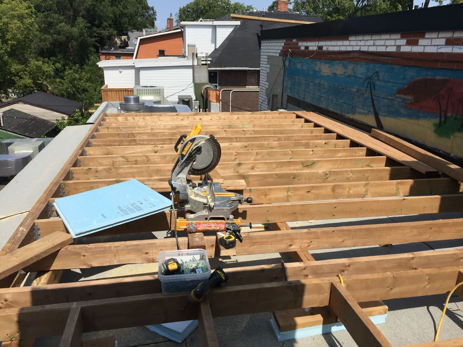 Deck joists and framing on a rooftop with a mitre saw, before the boards go on.