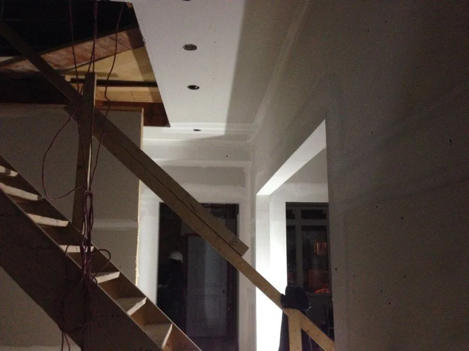 A staircase with a plain wood stringer beneath a white trimmed ceiling.