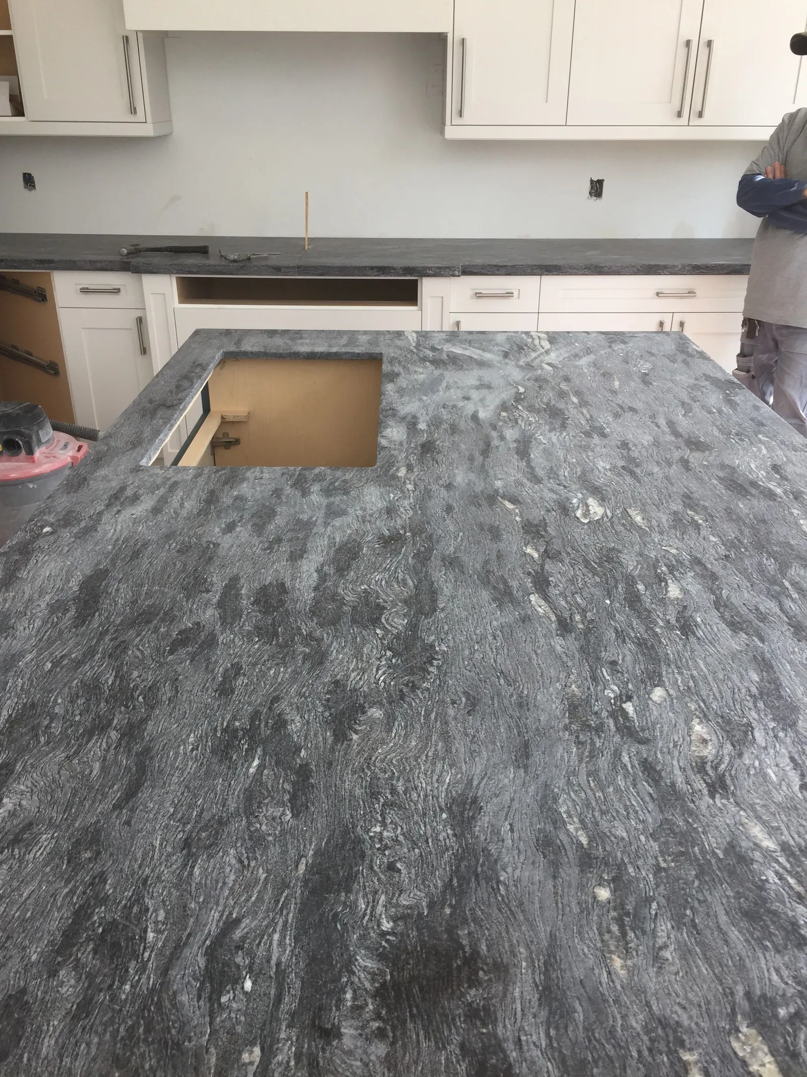 A slab of dark stone laid on a kitchen island frame, with a sink cut-out.