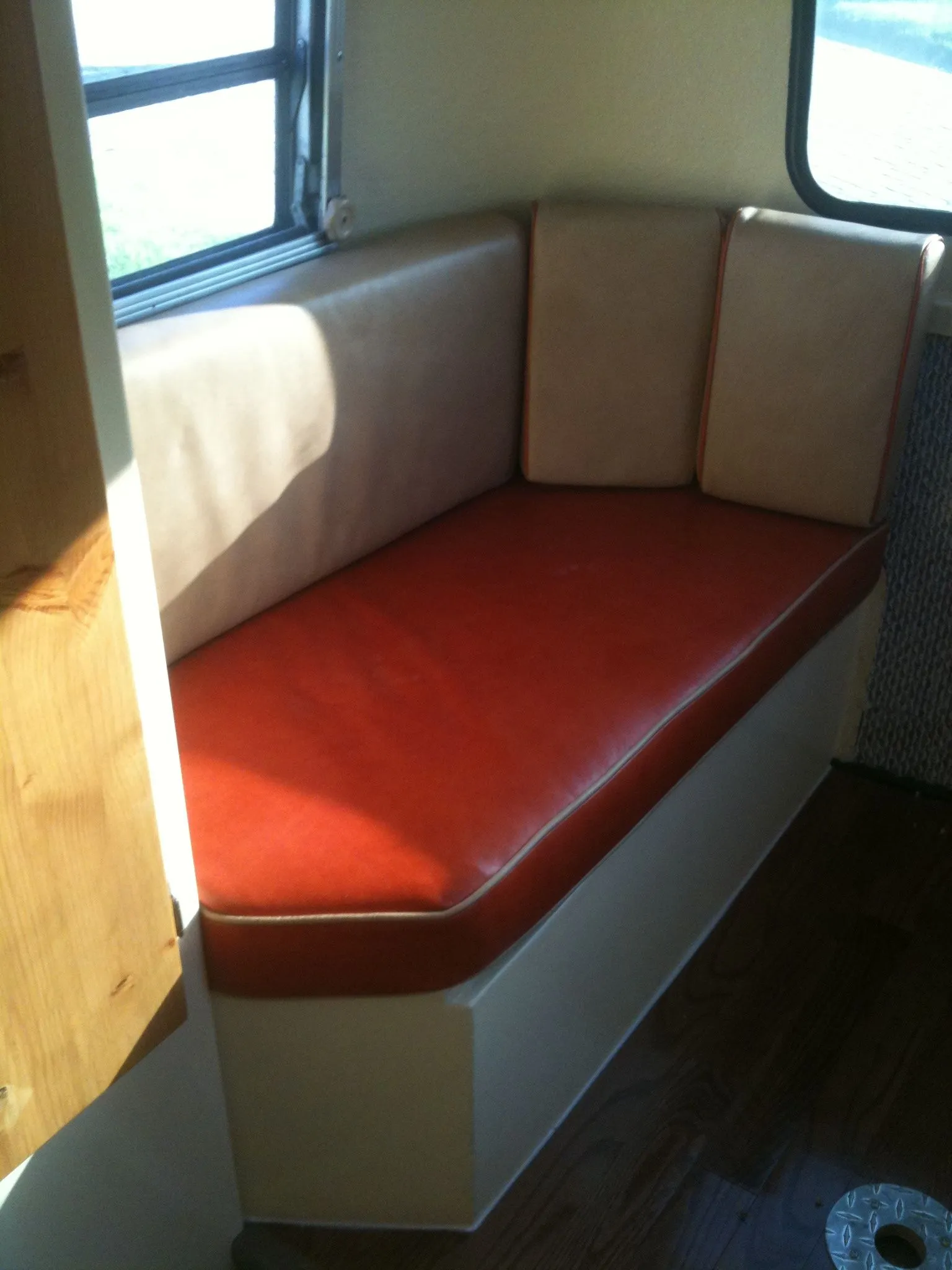 A red dinette bench and cream panels inside the trailer.