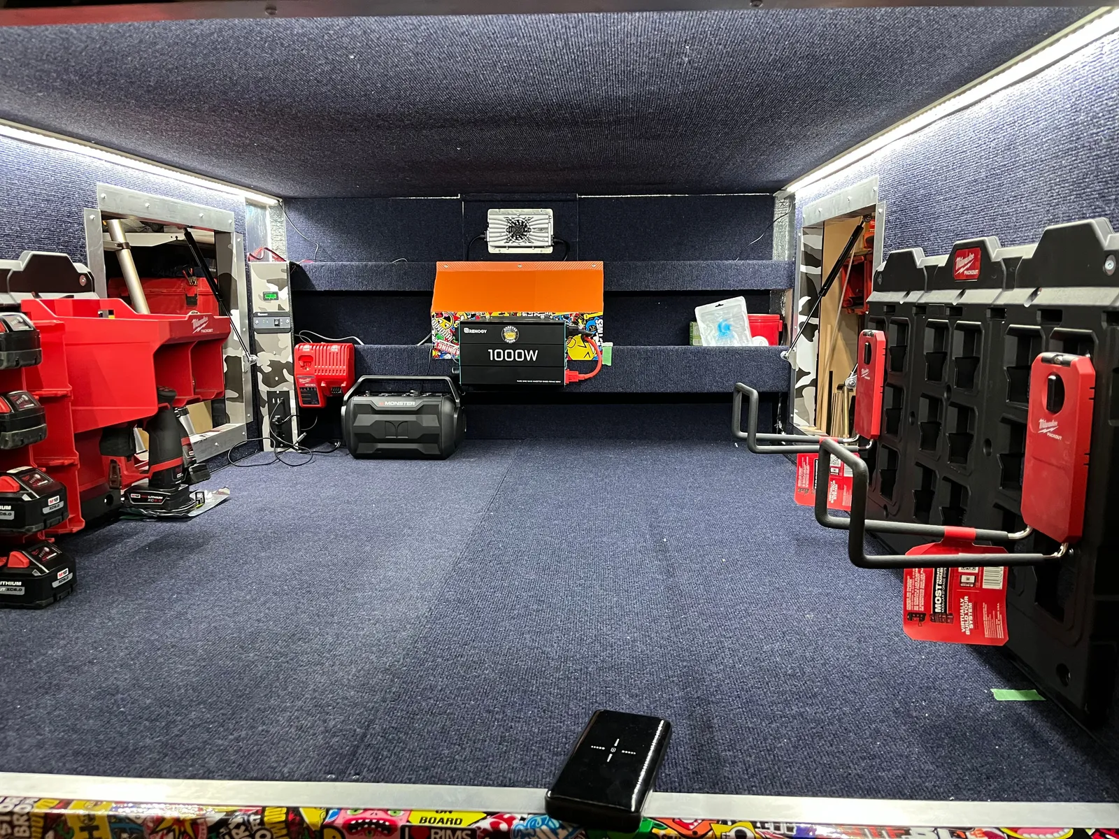 The inside of the cabin, carpeted, with LED strip lights and red tool cases.